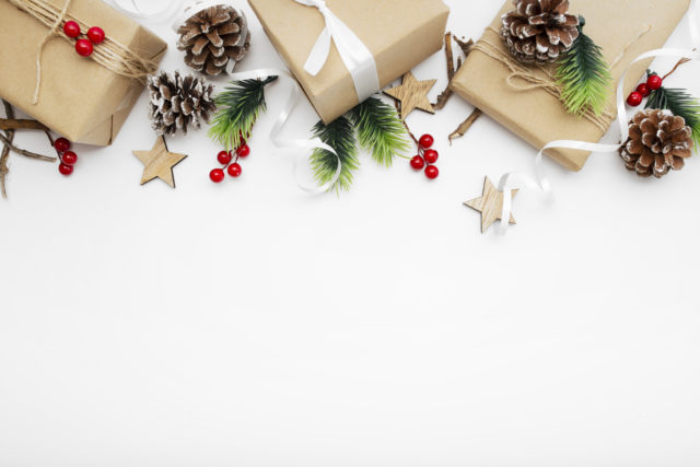 Top view of Christmas composition with gift box, ribbon, fir branches, cones, anise on white background with copy space.