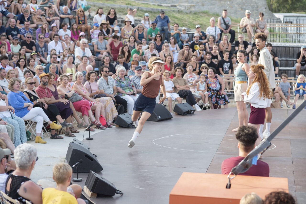Festival d'Alba 2023. Artiste qui court devant le public installé dans le Théâtre Antique D'Alba la Romaine